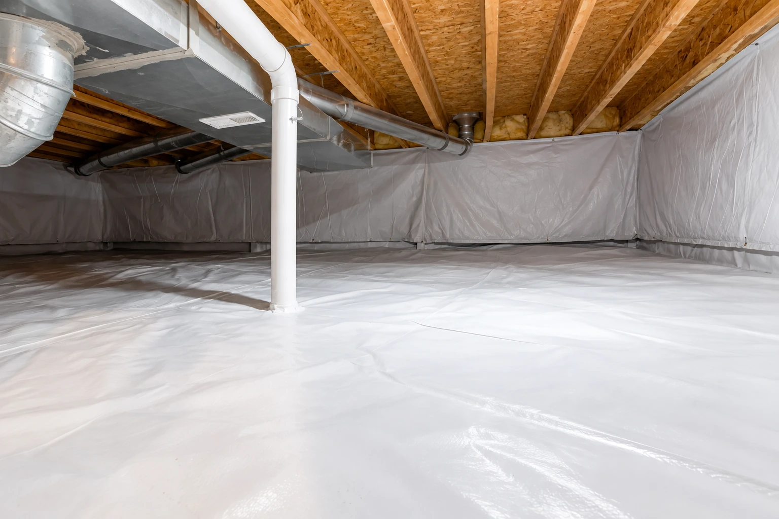 A crawl space has a white vapor barrier covering the floor and lower walls beneath exposed joists and ducts.